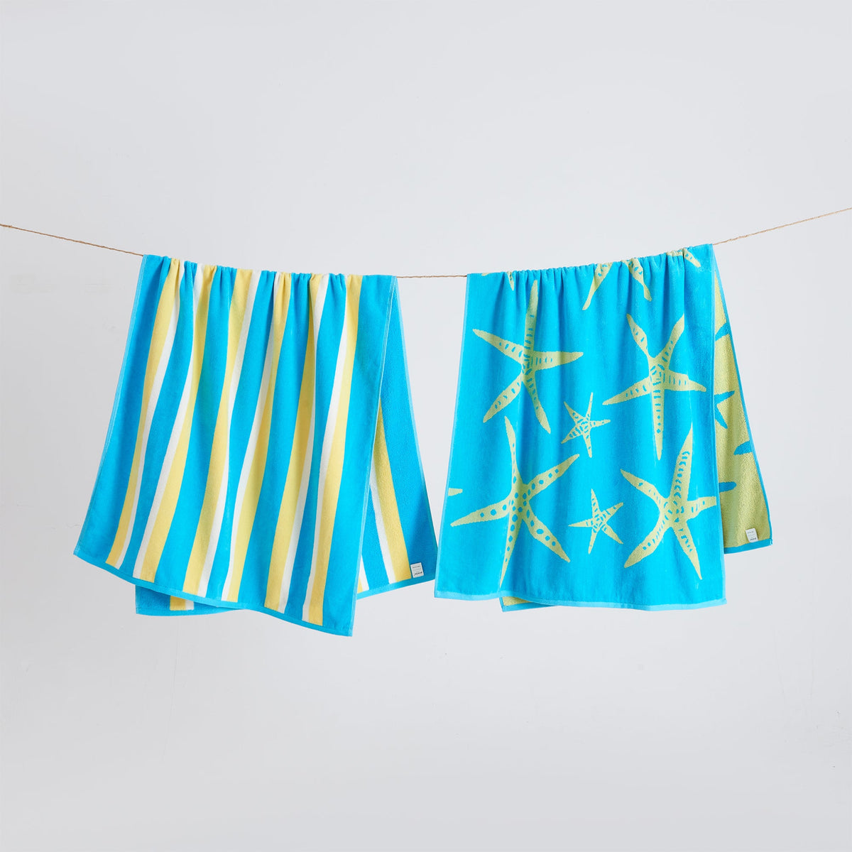 Blue cotton velour beach towels hanging on a line with starfish prints