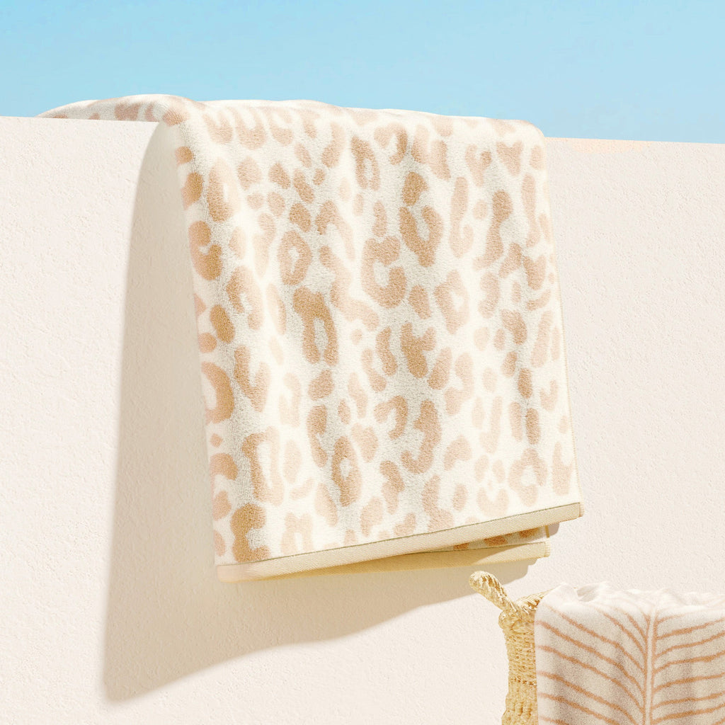 Beige leopard-print cotton velour beach towel folded over an armrest