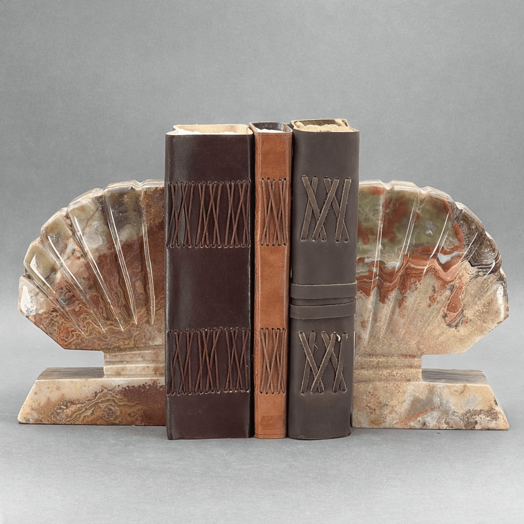 Gemstone shell bookends with two upright brown books and stepped geometric carving