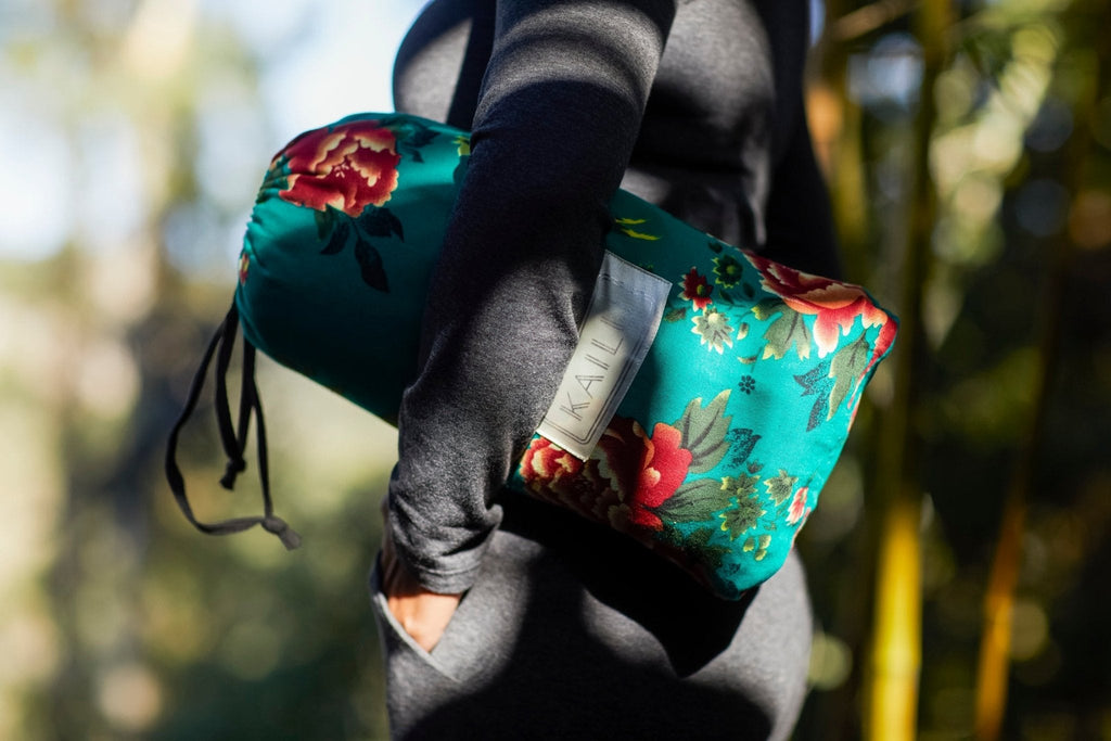 Teal floral silk throw pouch carried in a black drawstring bag.