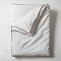 White silk throw with dark piping, folded flat.