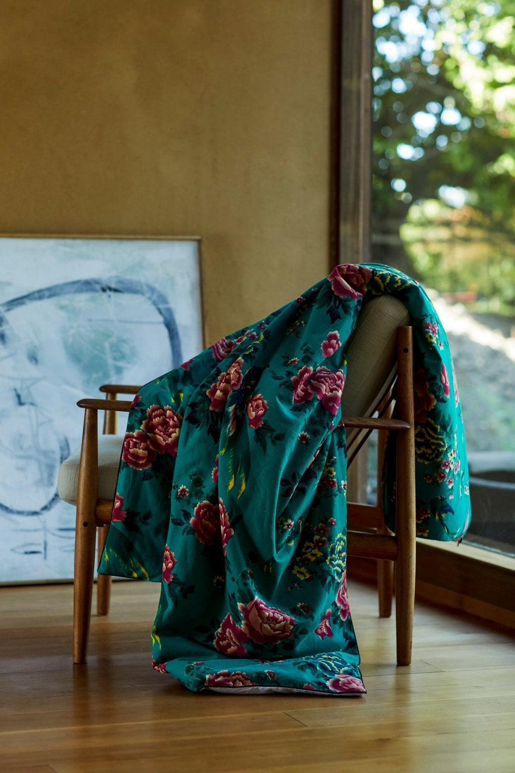 Teal floral silk throw draped over chair, with carry pouch nearby.