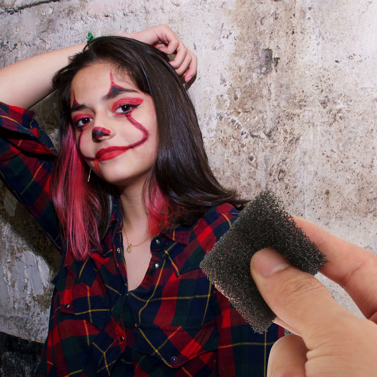 Black foam makeup sponge applying costume face paint on a person’s cheek