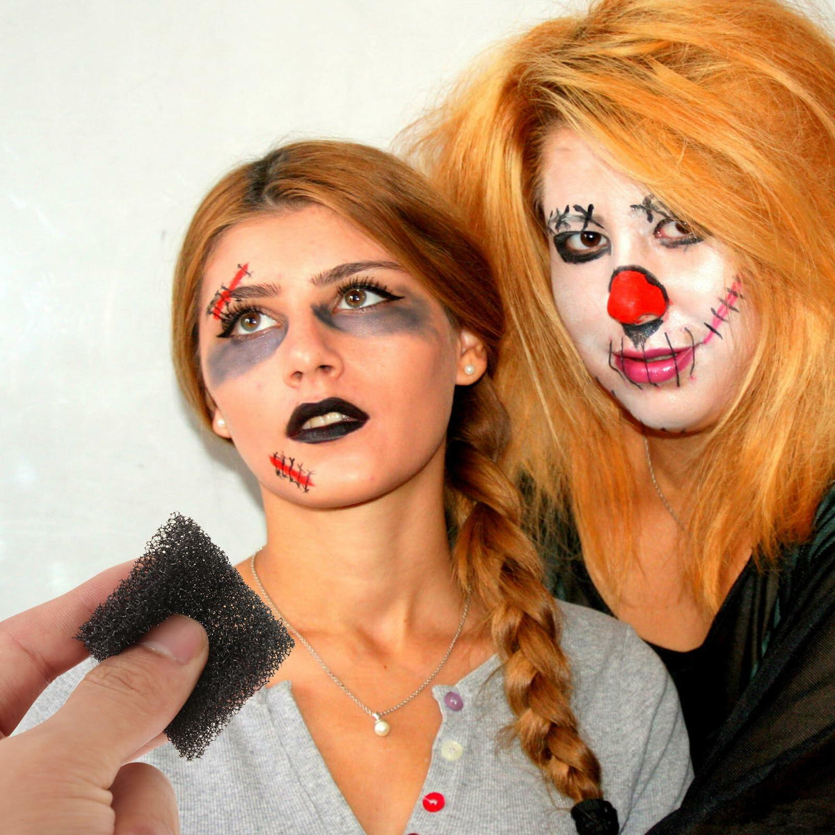 Black foam sponge held near painted faces for Halloween costume makeup