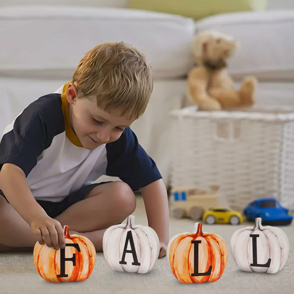 Child placing pumpkin wood letter signs on floor blocks: F, A, T, L