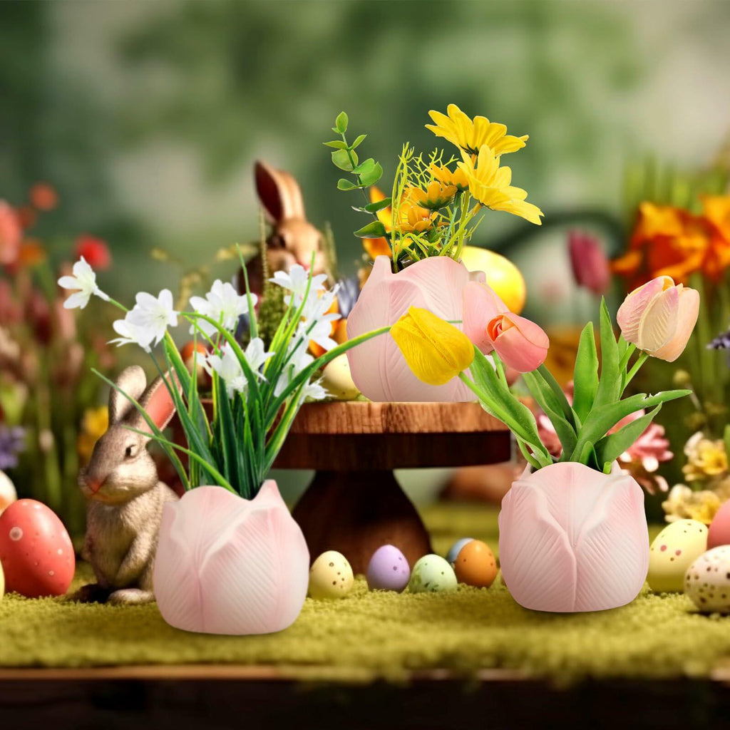 Three pink tulip-shaped ceramic mini vases holding colorful spring blooms