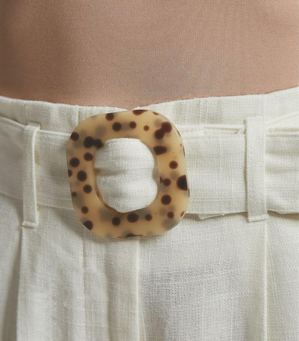 White linen pants front closure with tortoise-pattern belt buckle and button