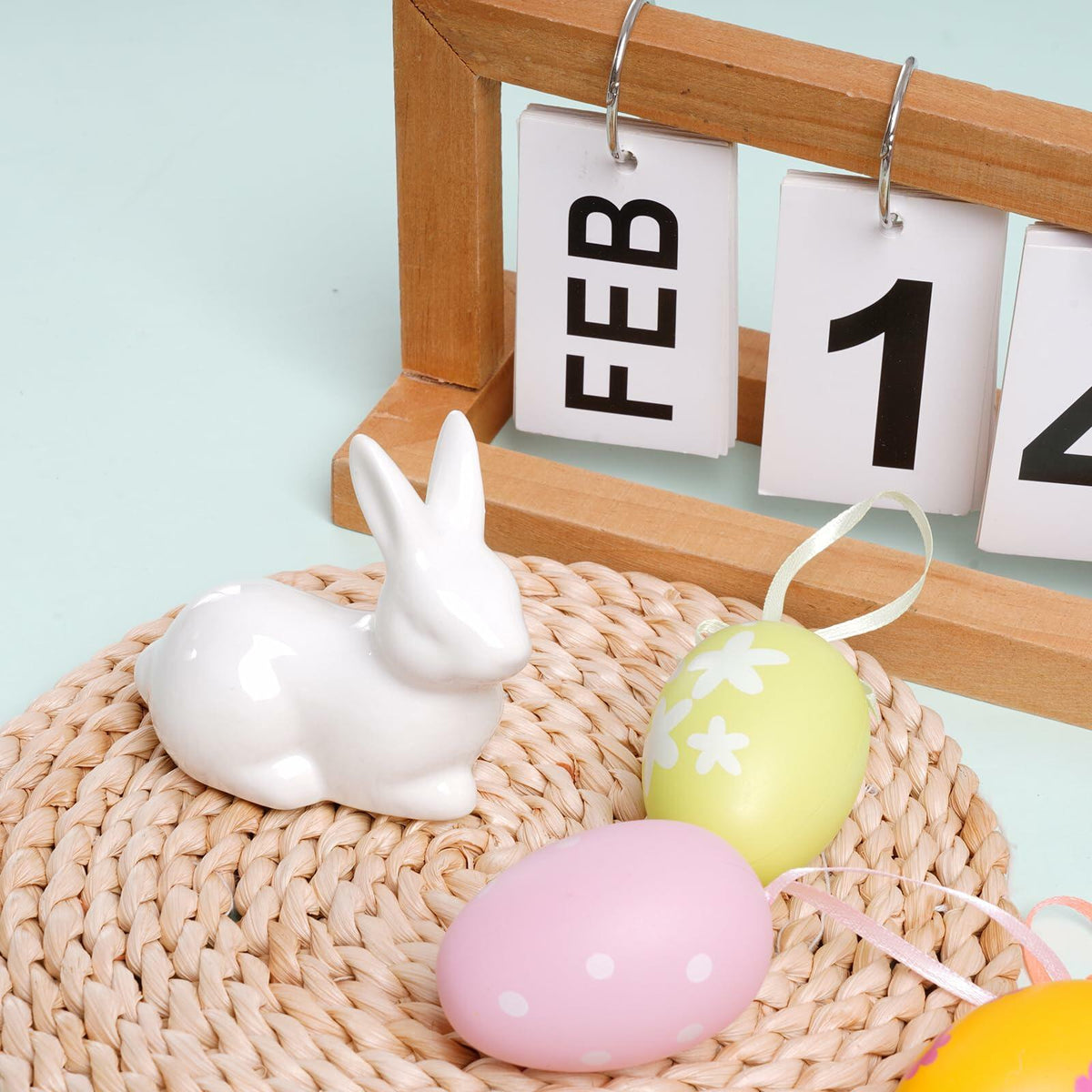 White ceramic Easter bunny figurine on woven mat, glossy seated rabbit with upright ears.