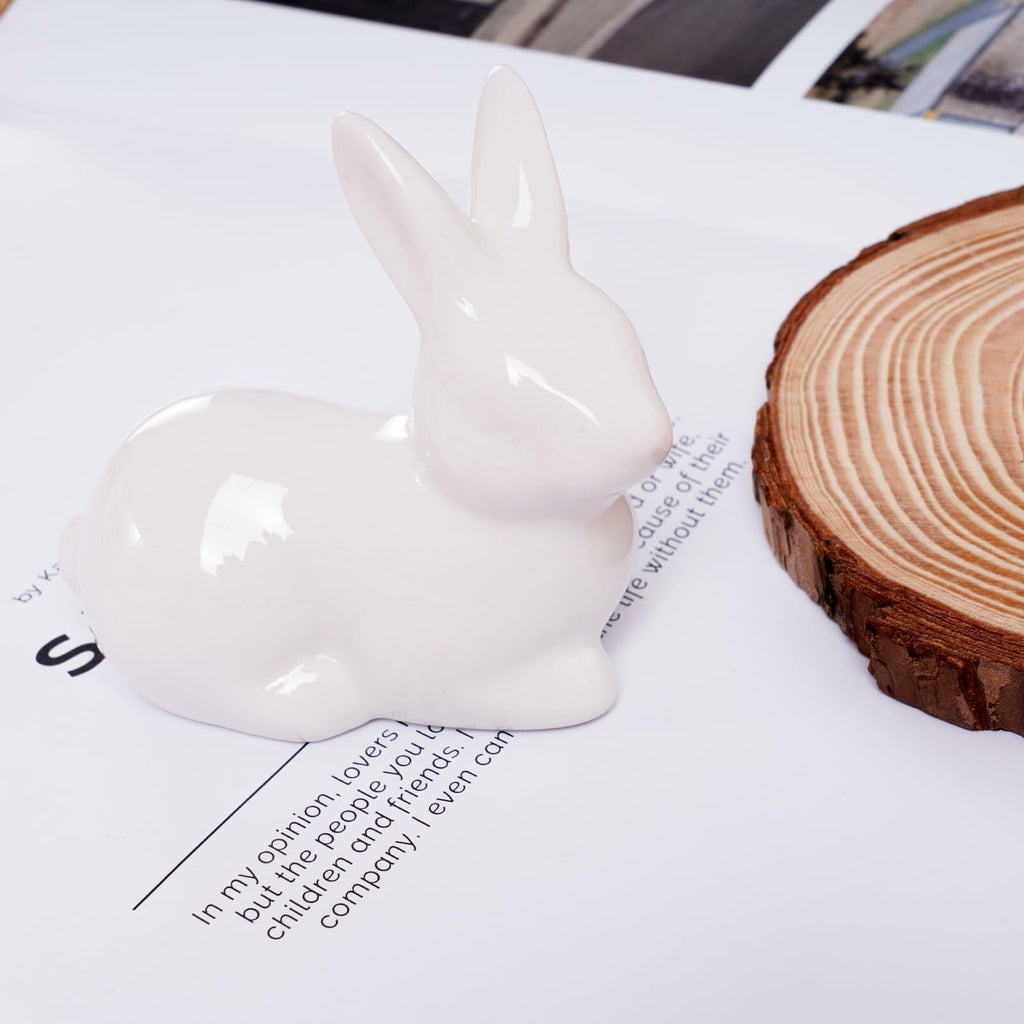 White ceramic Easter bunny figurine, glossy seated rabbit on magazine surface, upright ears.
