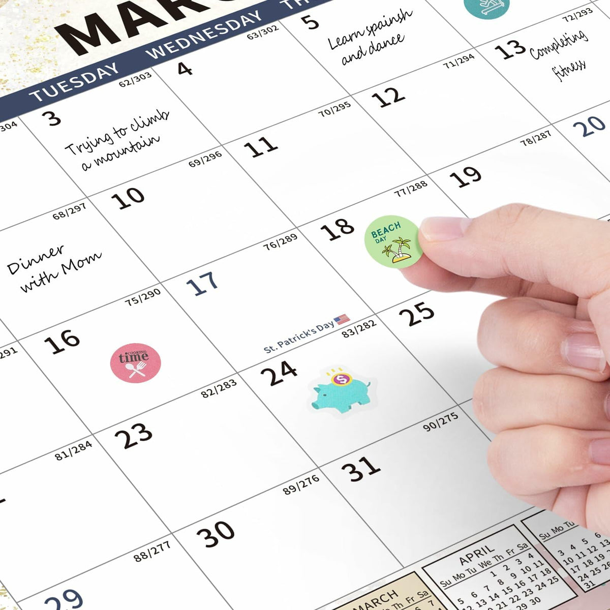 Close-up of fingers marking dates on monthly wall calendar with stickers