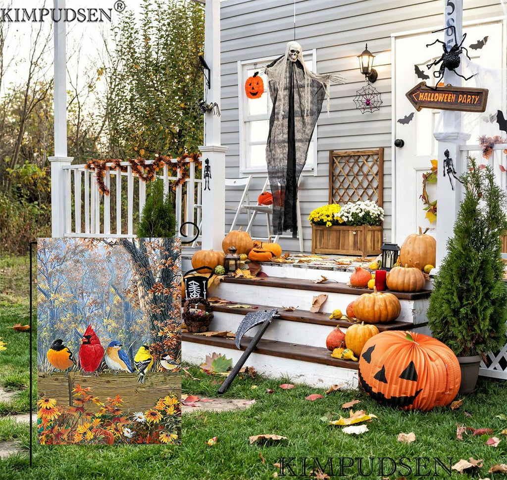 Garden flag with fall bird artwork hanging in an autumn yard among pumpkins