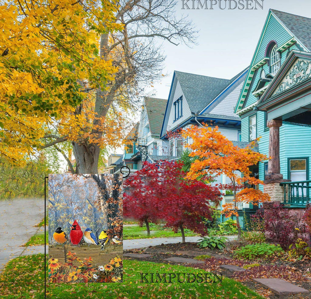 Double-sided garden flag with fall bird scene displayed outdoors near a house