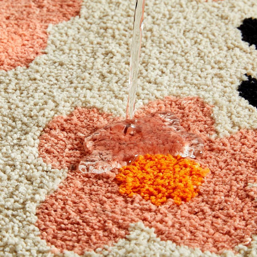 Close-up of beige bath mat pile with orange, peach, and coral floral accents