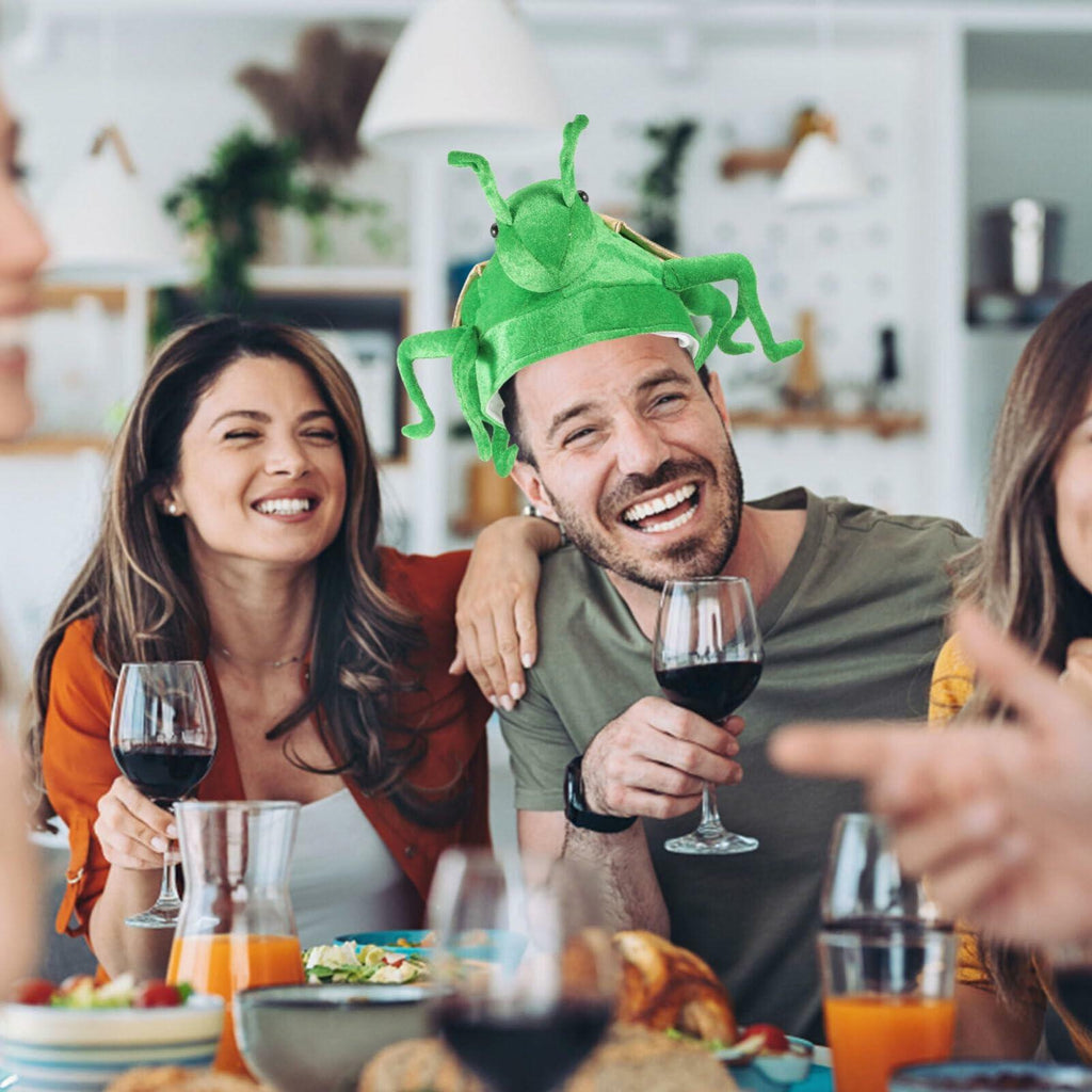 Plush green frog costume hat with beige ear panel, worn by an adult at a party