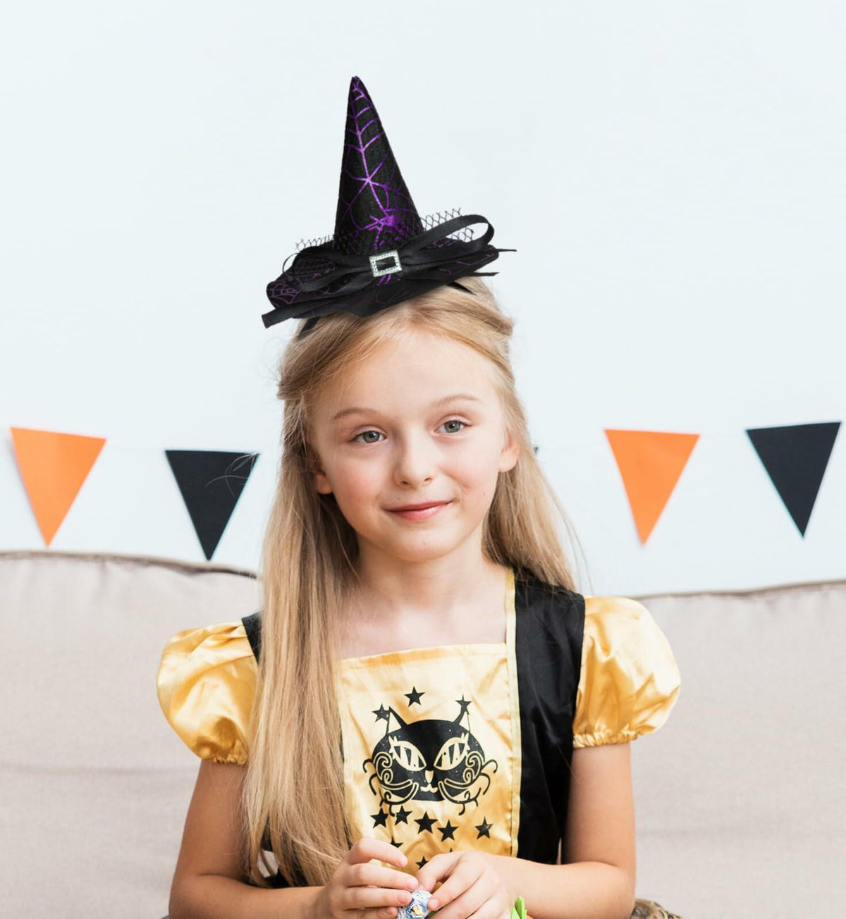 Purple witch hat headband with black bow and elastic band on a girl’s head