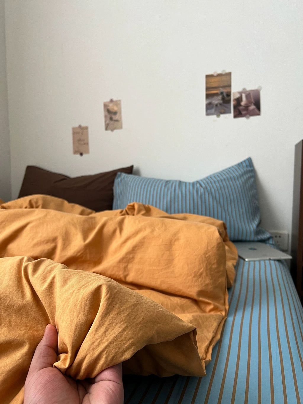 Orange bedding duvet and pillow on blue striped base, close to the corner