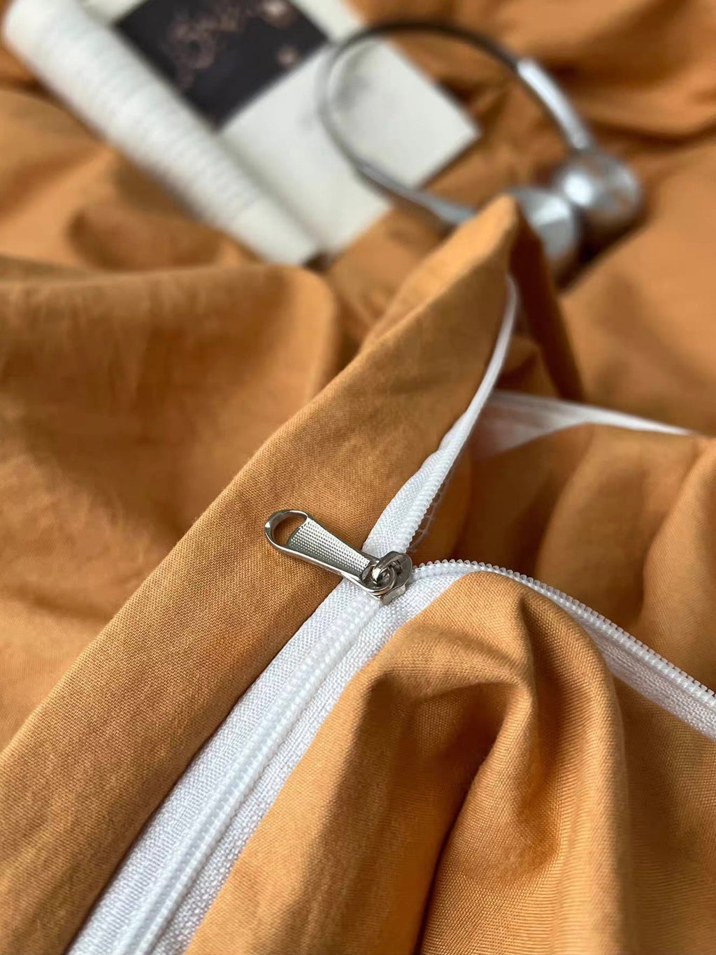 Close-up of orange bedding duvet zipper with white trim and metal pull