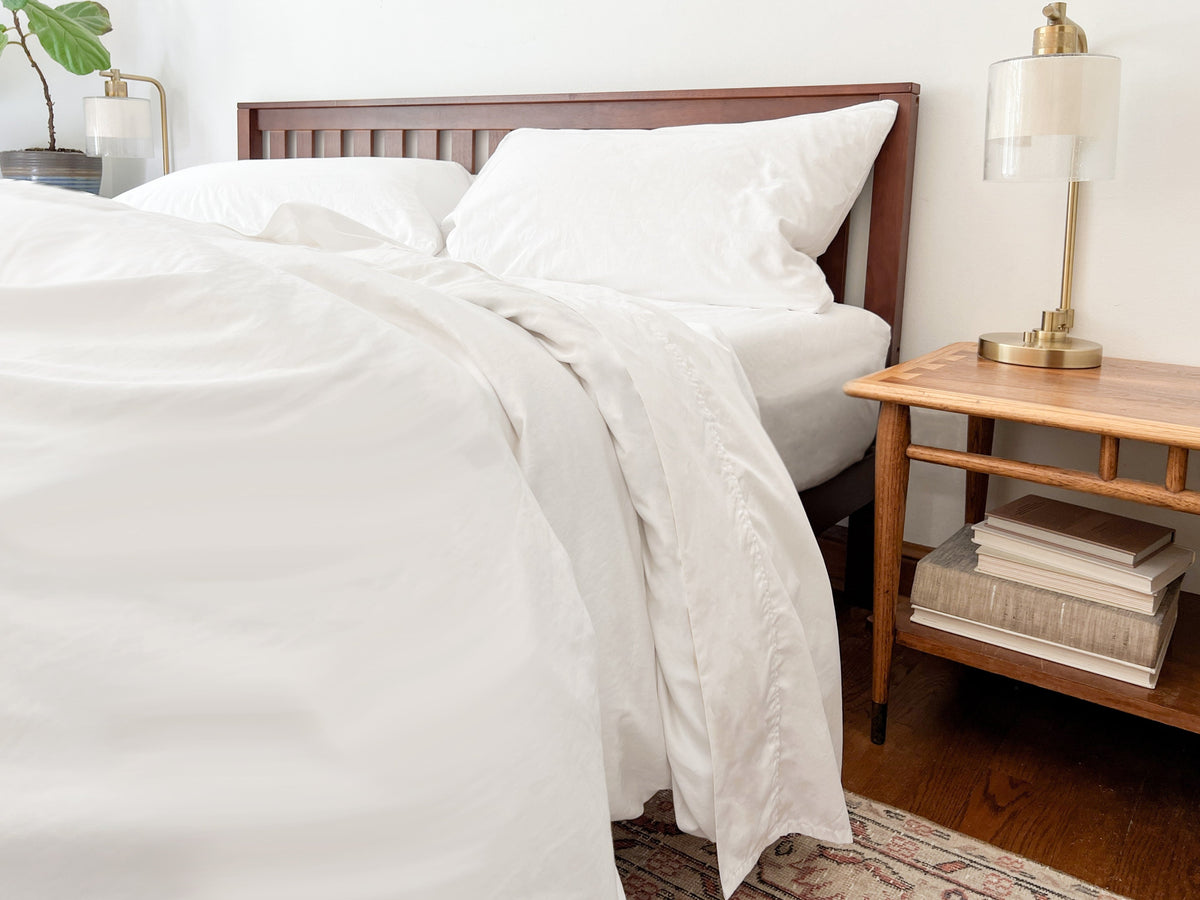 Pure white bed sheet set with crisp percale weave, neatly draped on mattress