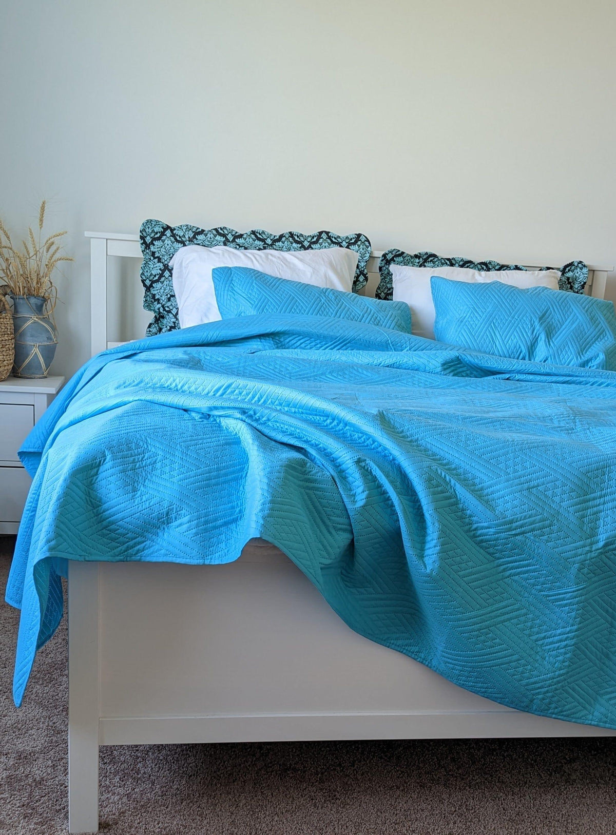 Turquoise teal lightweight quilted bedspread with wave stitch pattern on a bed