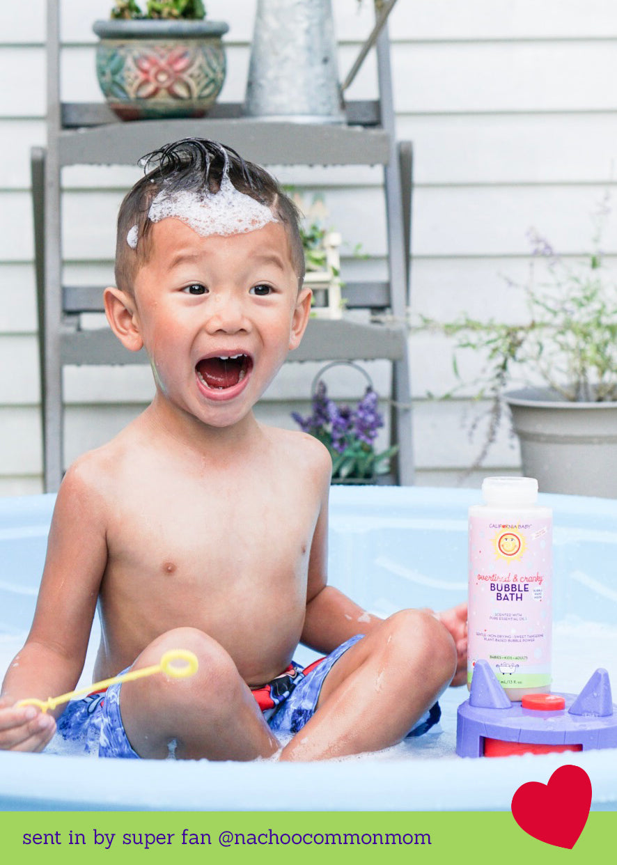 Pink bubble bath bottle beside splashing child in a pool.