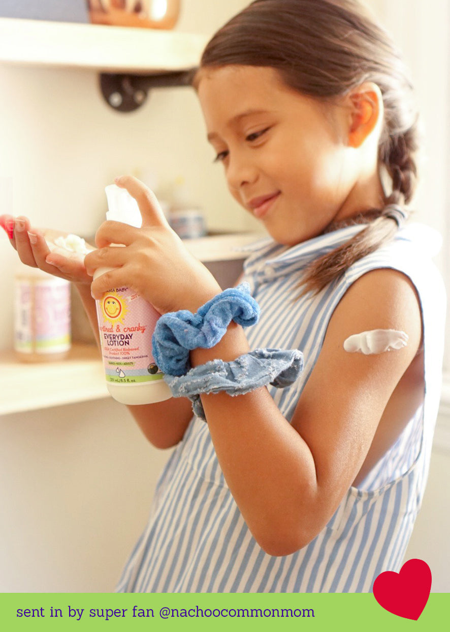 Child applying lotion from a white-pump bottle with pink label
