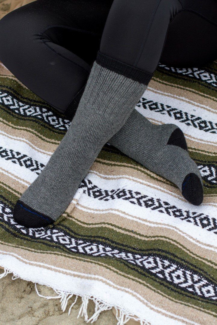 Grey alpaca socks with black toe and folded cuff on striped rug