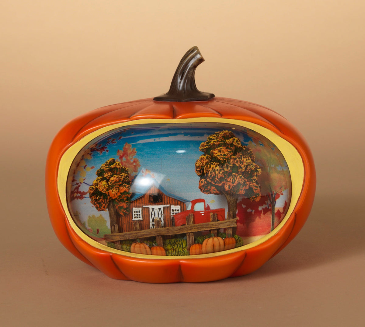Orange pumpkin-shaped lighted water globe with trees and house scene behind clear globe