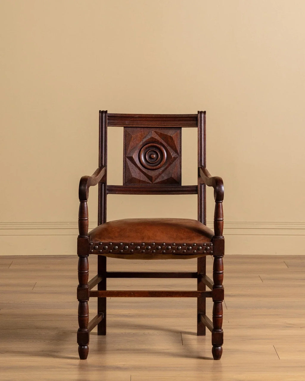 Wood armchair with diamond back panel, circular medallion, and brown studded seat