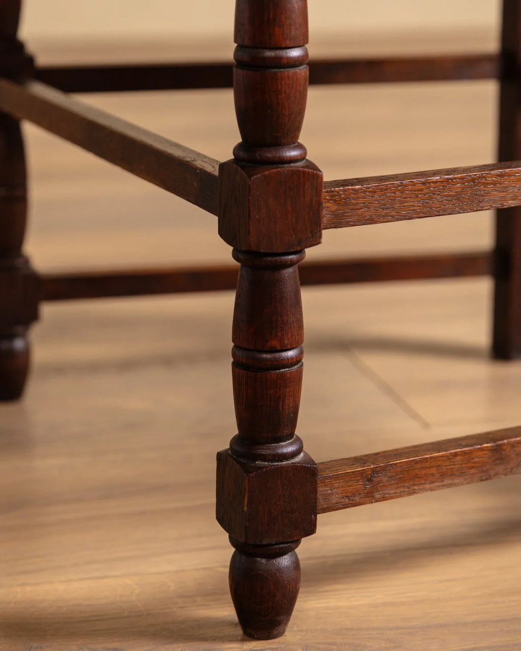 Close-up of turned wood leg and stretcher frame on an open-arm chair