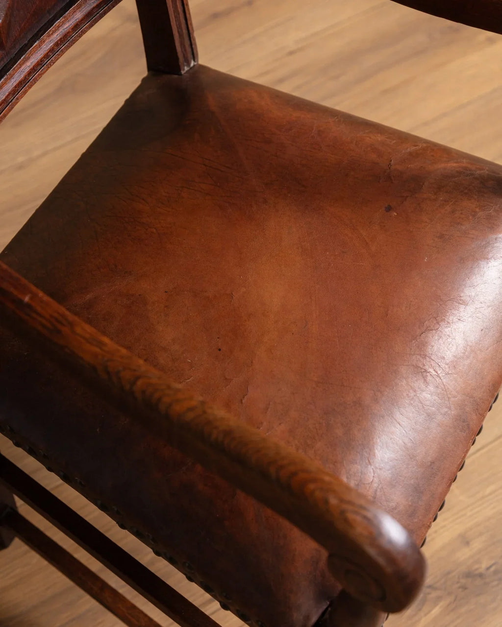Close-up of dark brown leather chair seat with smooth patina and rounded edge