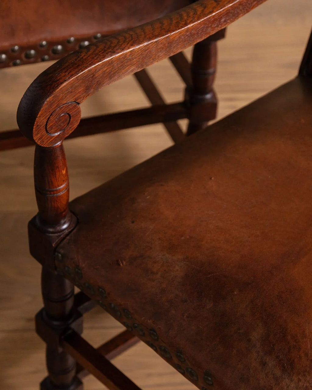 Close-up of brown leather cushion on dark wood armchair with turned legs
