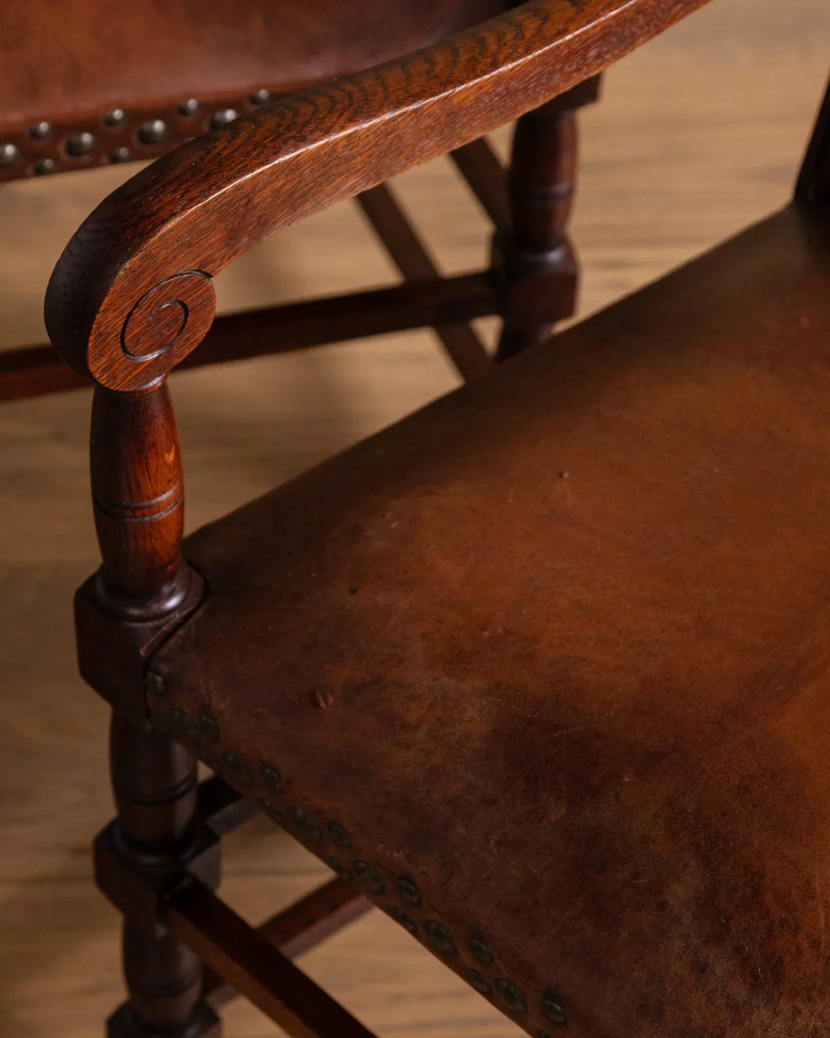 Close-up of brown leather cushion on dark wood armchair with turned legs