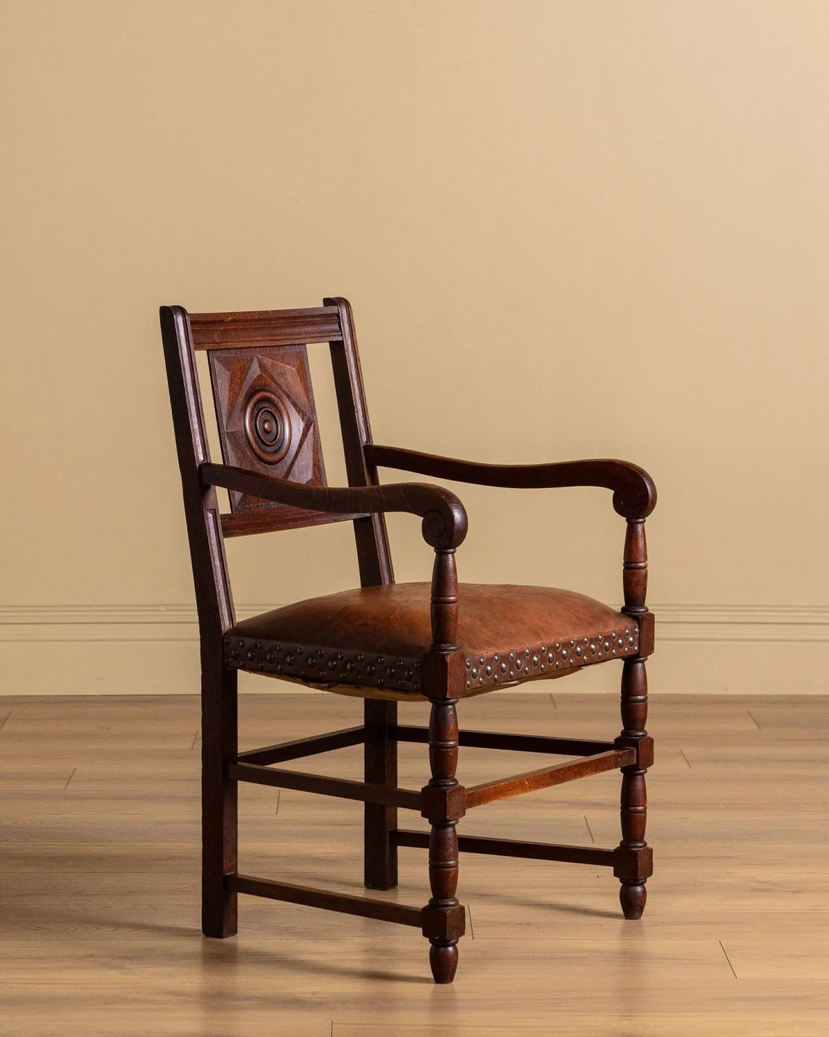 Wood-framed armchair with curved arms, brown upholstery, and studded seat trim