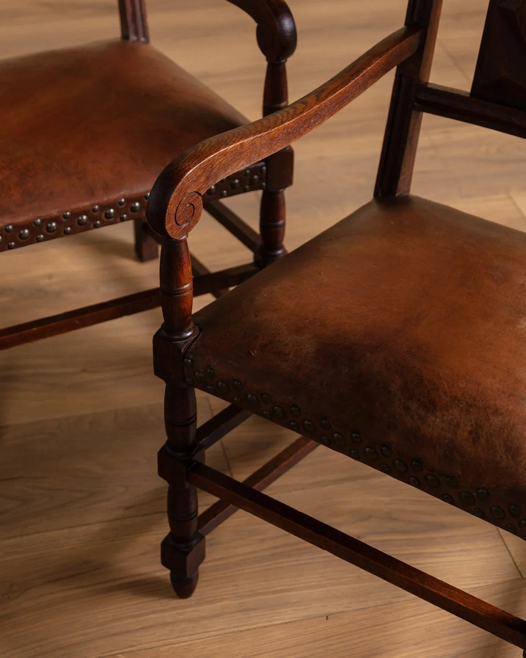 Close-up of turned wood arm and leg details on brown upholstered armchair