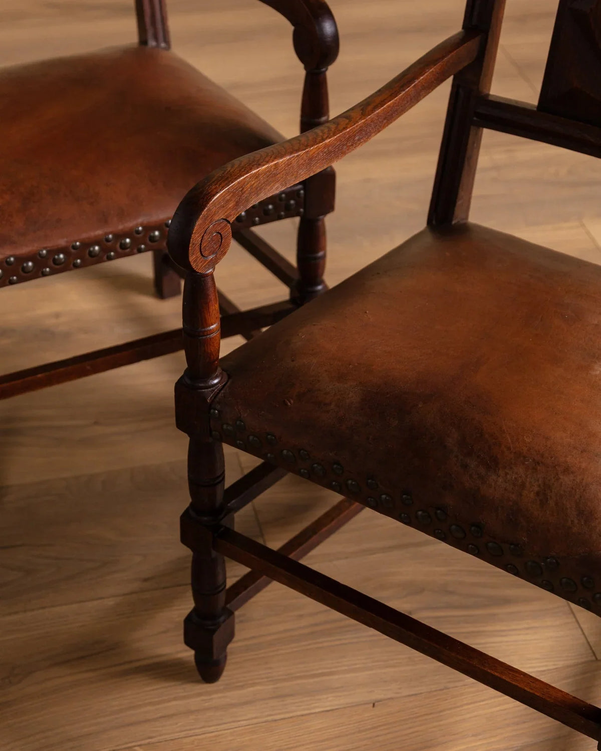 Close-up of turned wood arm and leg details on brown upholstered armchair