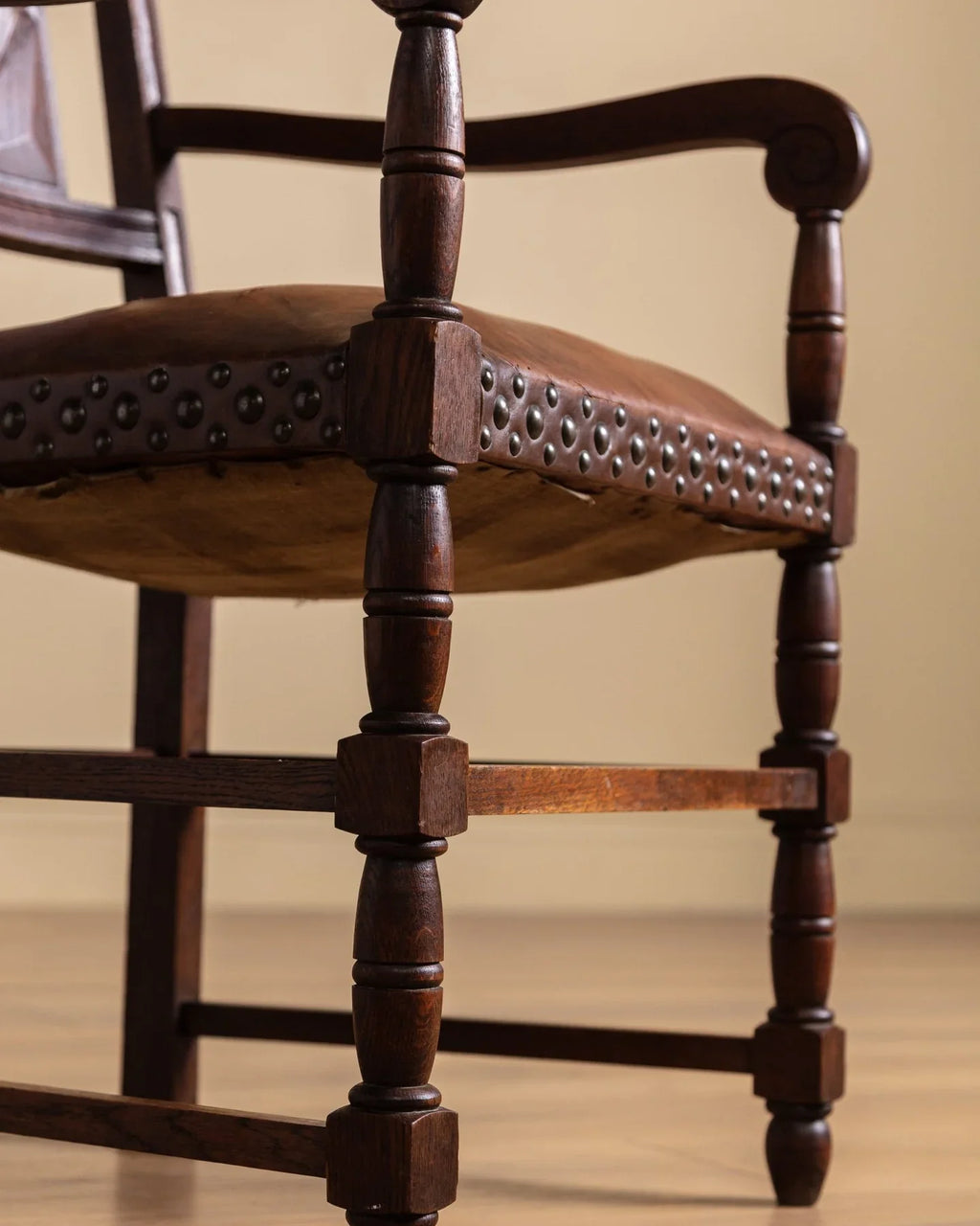 Wood open-arm chair with studded leather seat rail and turned spindle legs