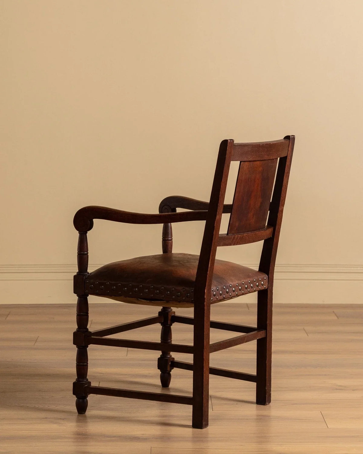 Brown leather-upholstered armchair with curved open arms and nailhead trim