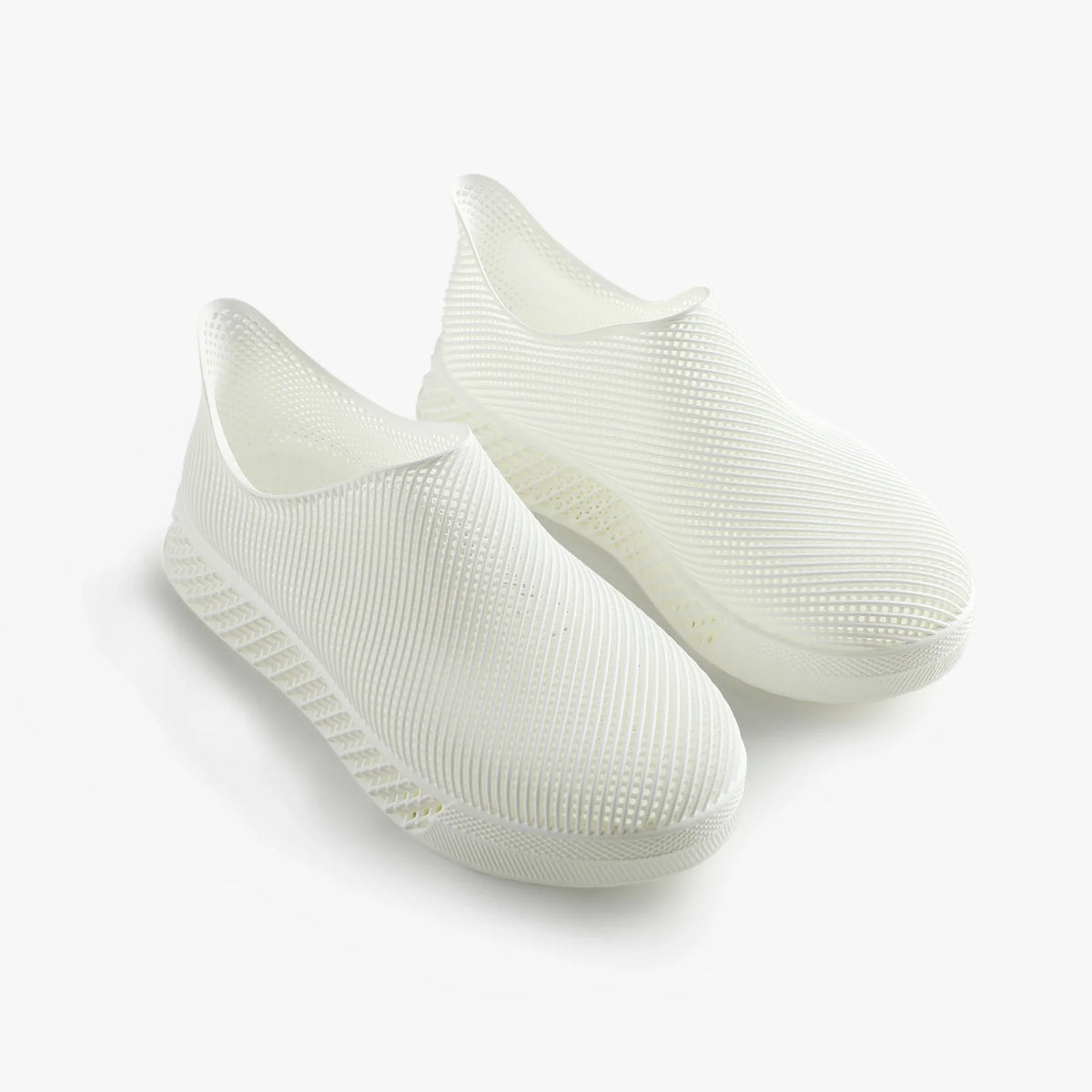 Pair of white 3D printed slip-on sneakers with ribbed texture and cushioned sole
