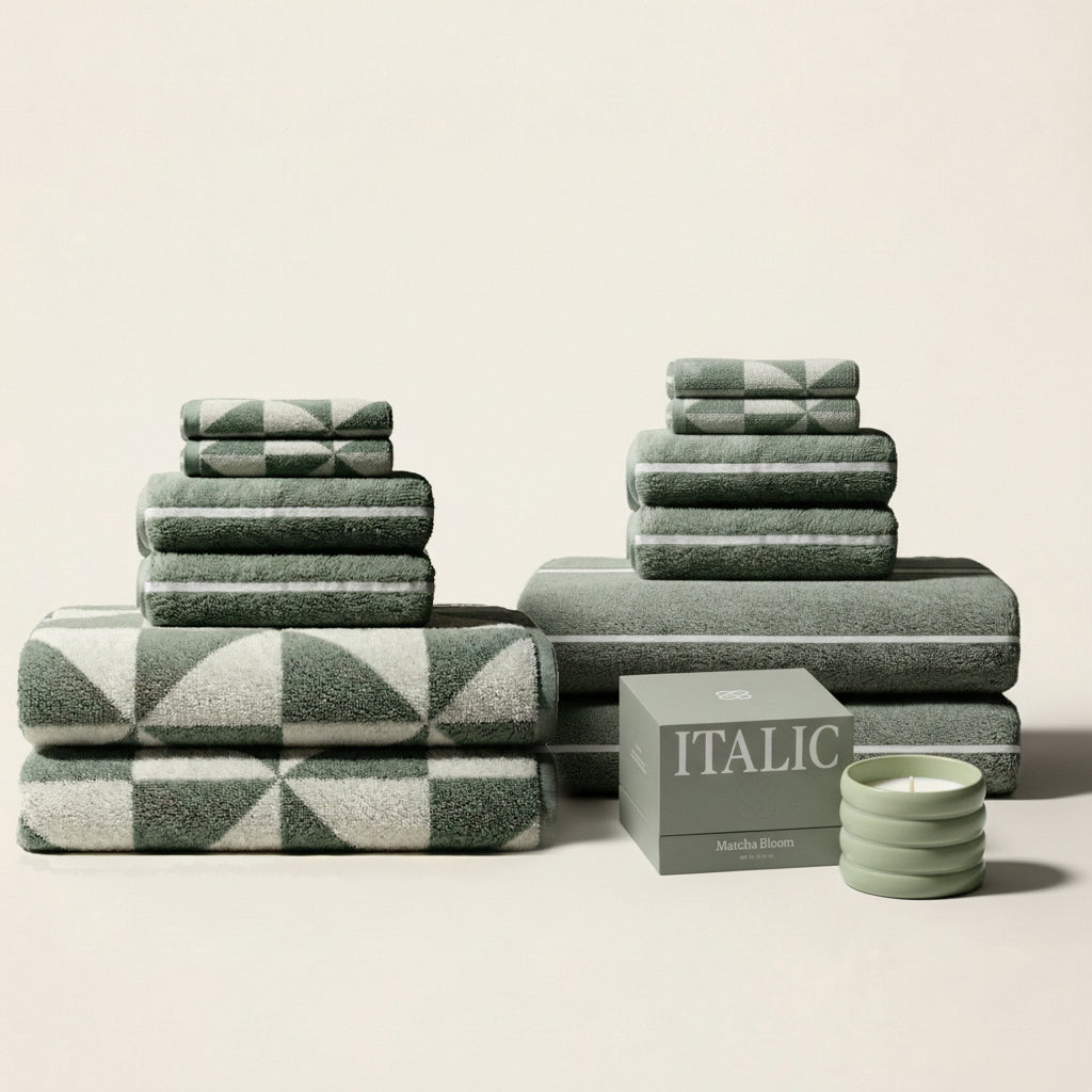 Stacked sage and ecru cotton towels, including a geometric pattern towel and solid sage.