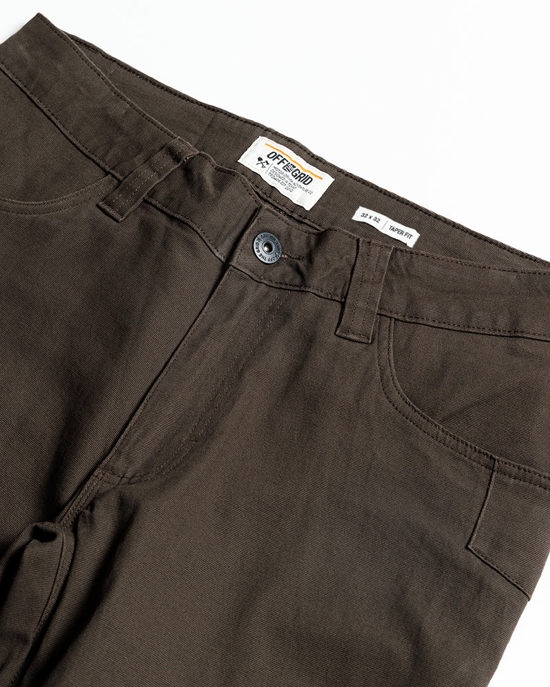 Dark brown pants waistband close-up with button fly, belt loops, and inner label.