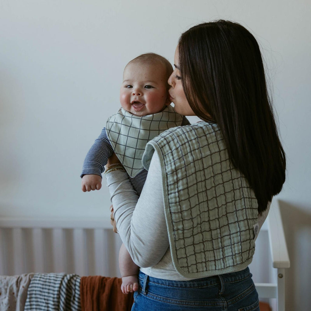 Muslin burp cloth with light grid pattern, folded over a parent’s shoulder