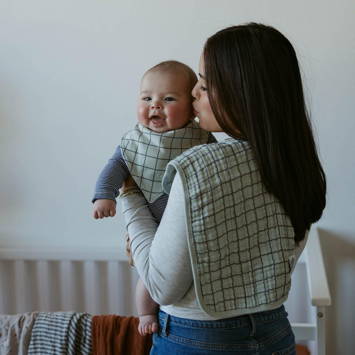 Muslin burp cloth with light grid pattern, folded over a parent’s shoulder