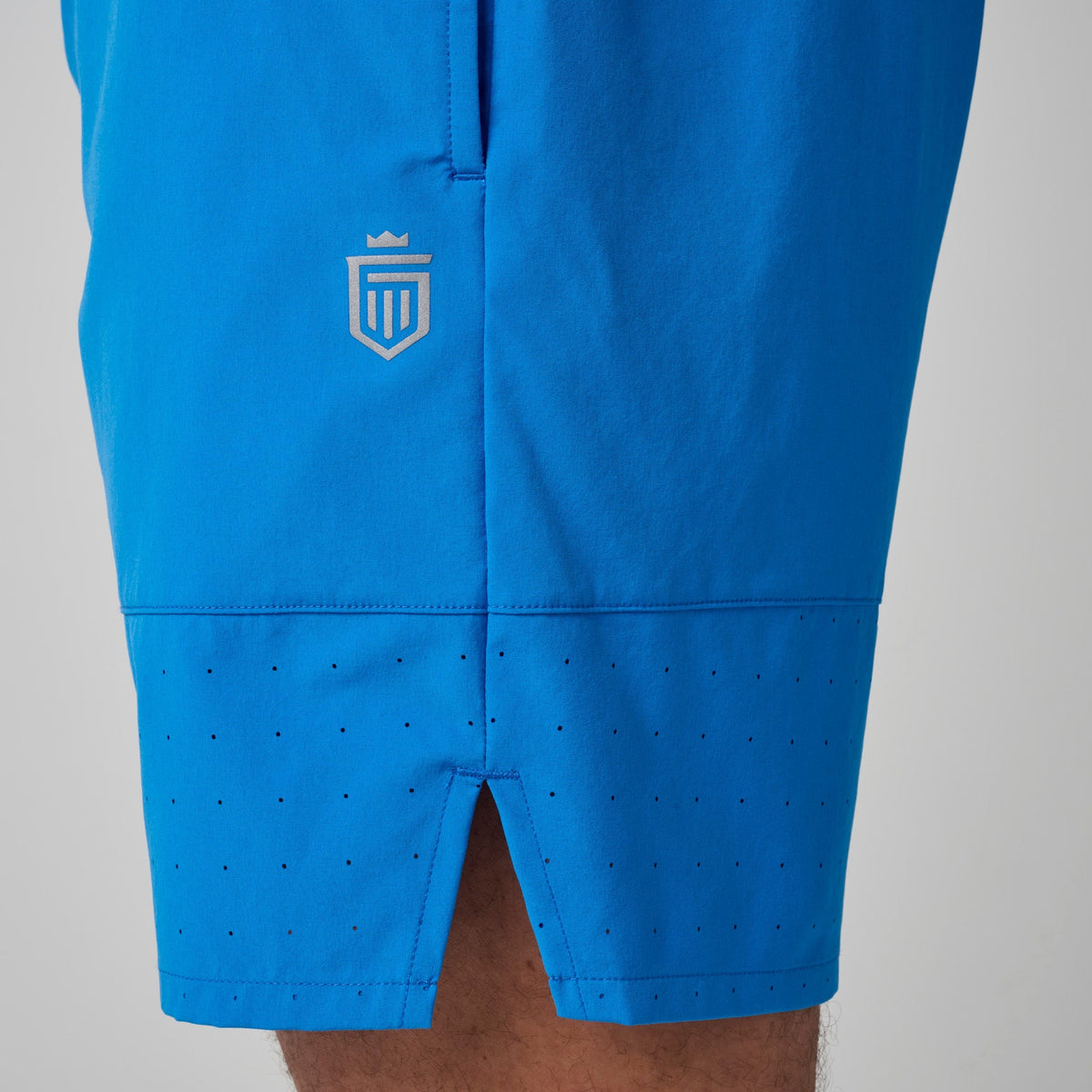 Bright blue shorts with small crest logo and perforated rear hem area