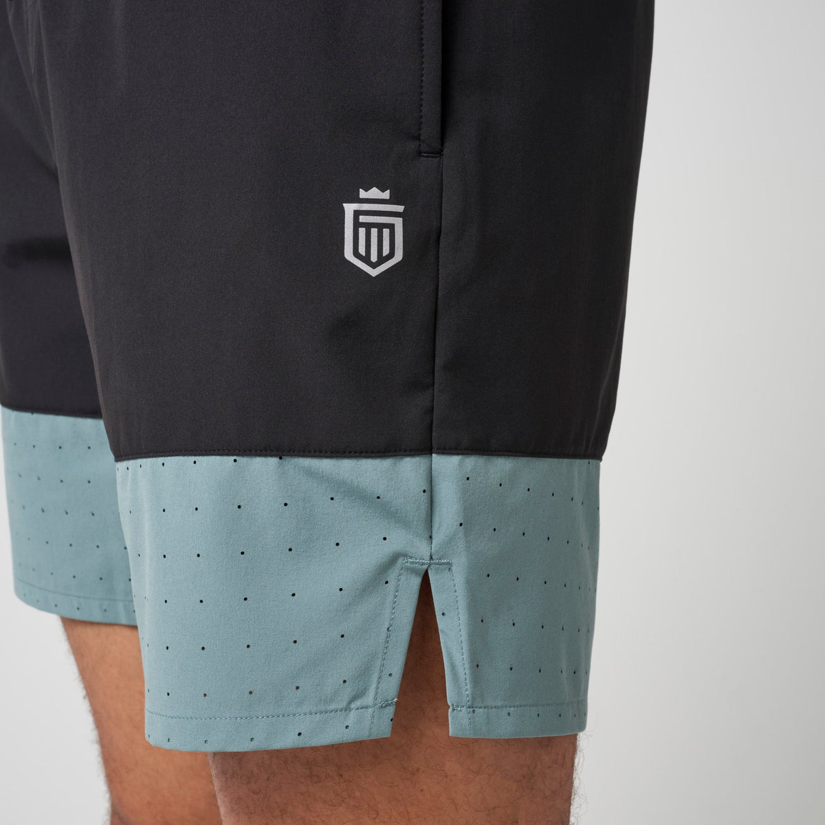 Black and steel blue performance training shorts with shield logo on left leg