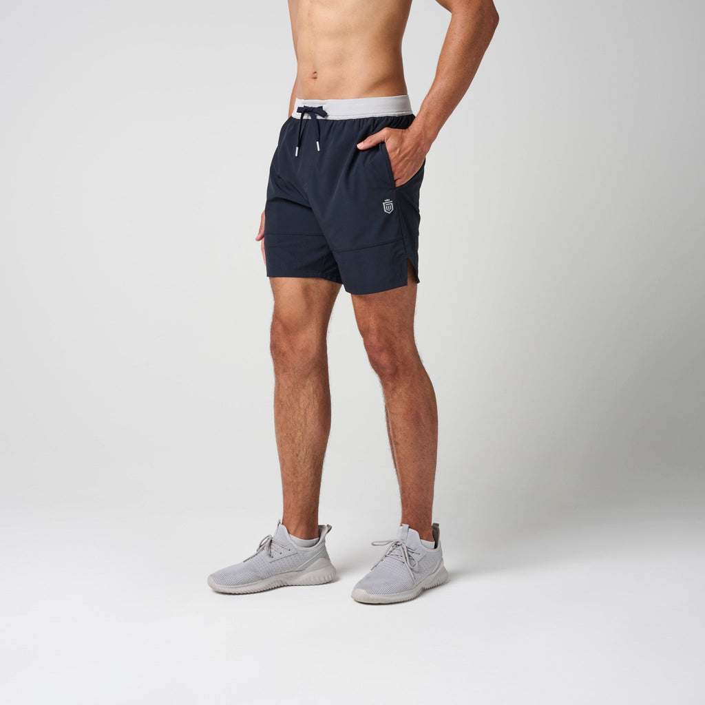 Navy athletic training shorts with gray waistband, drawstring, and small logo patch.