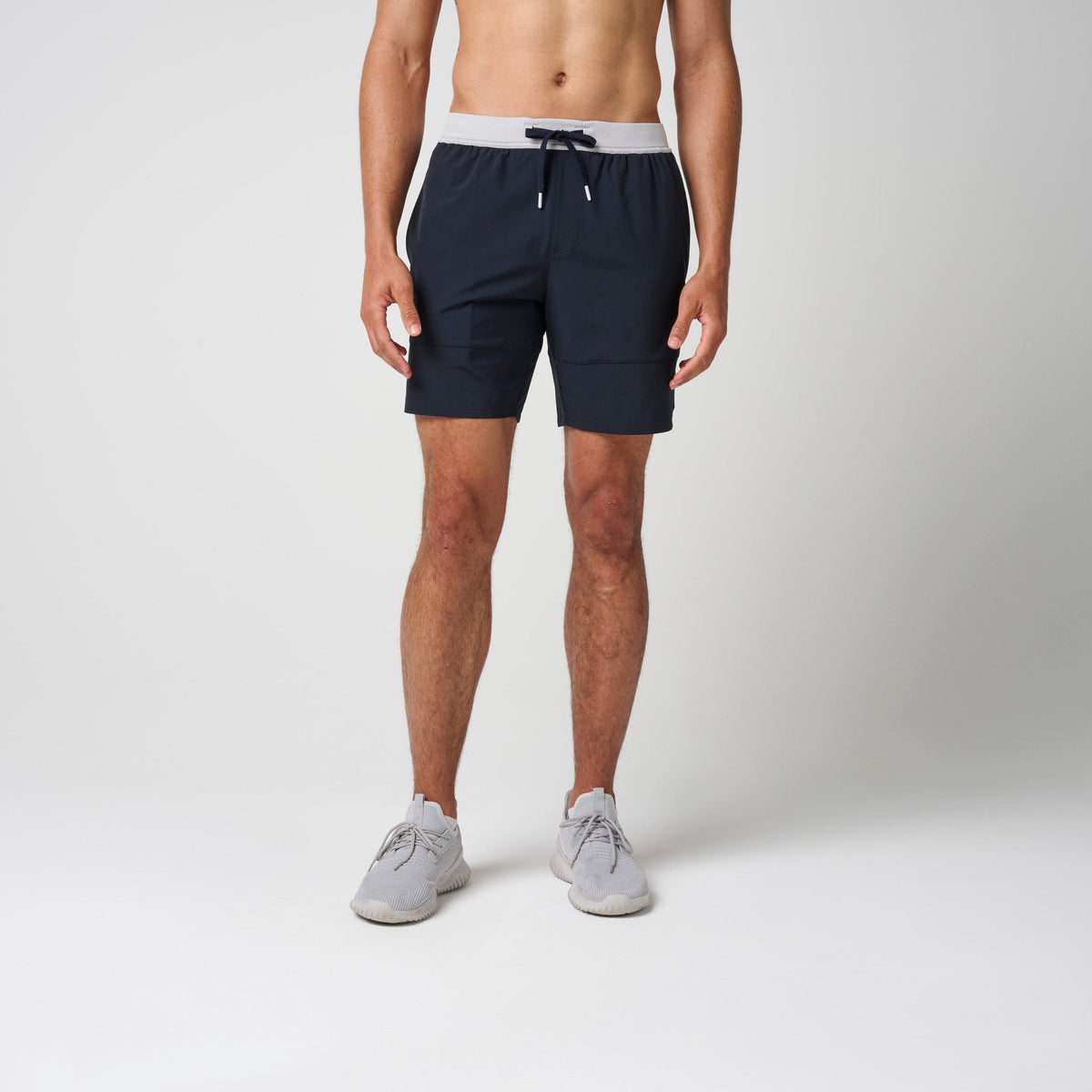 Navy performance training shorts with gray waistband, drawstring, and side pockets.