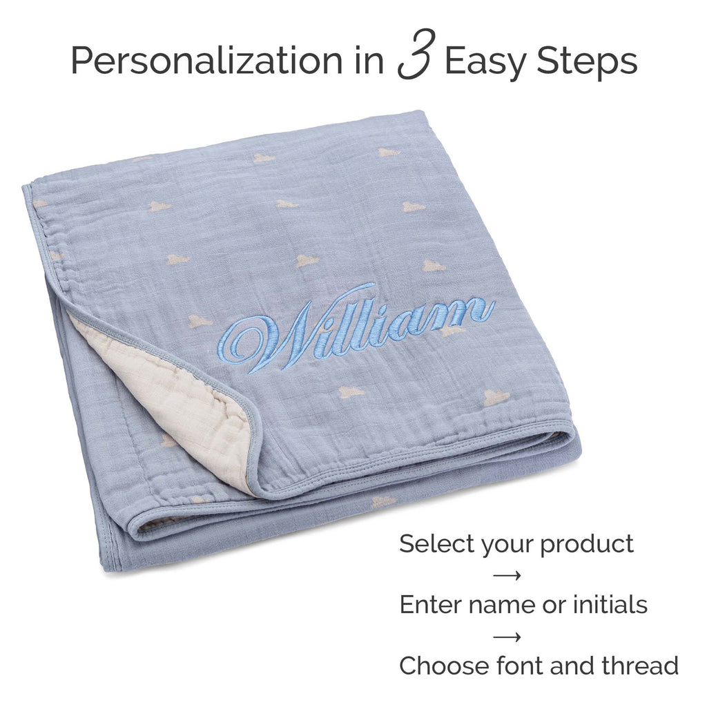 Blue muslin quilt folded, subtle speck motifs with blue embroidered name on edge
