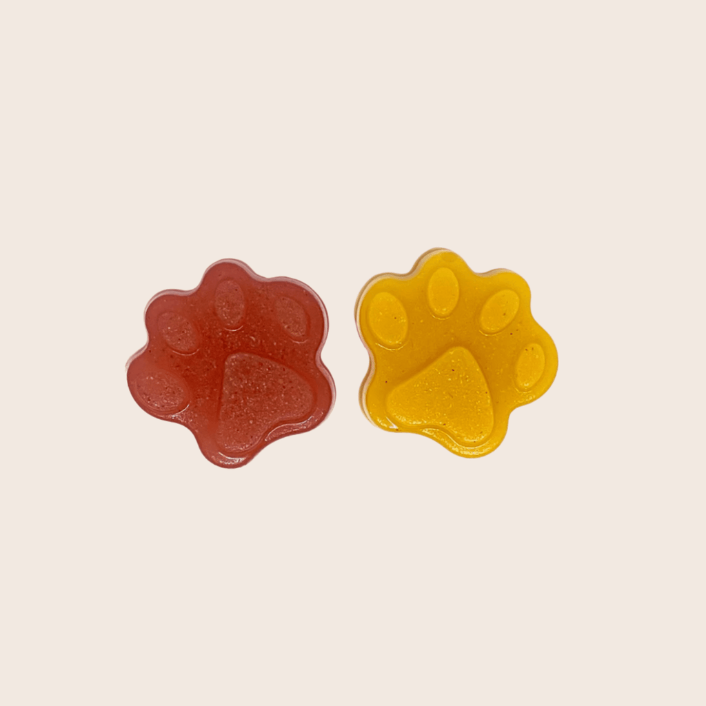 Two paw-shaped pet treats in red and yellow
