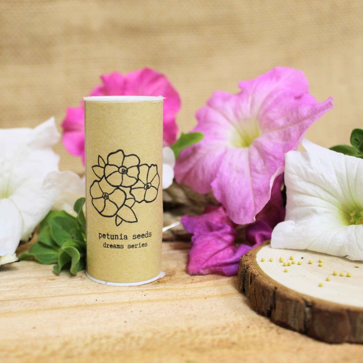 Seed tin beside pink and white petunias on a wooden surface