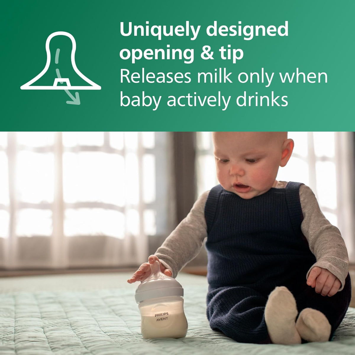 Baby seated on blanket holding a baby bottle with soft nipple